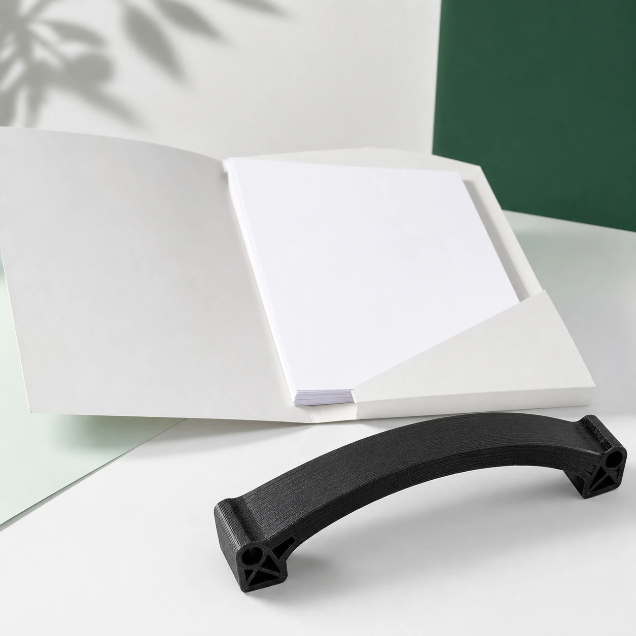Black PAHT-CF: black PAHT-CF curved sample coupon beside an open plain document folder containing only completely blank sheets