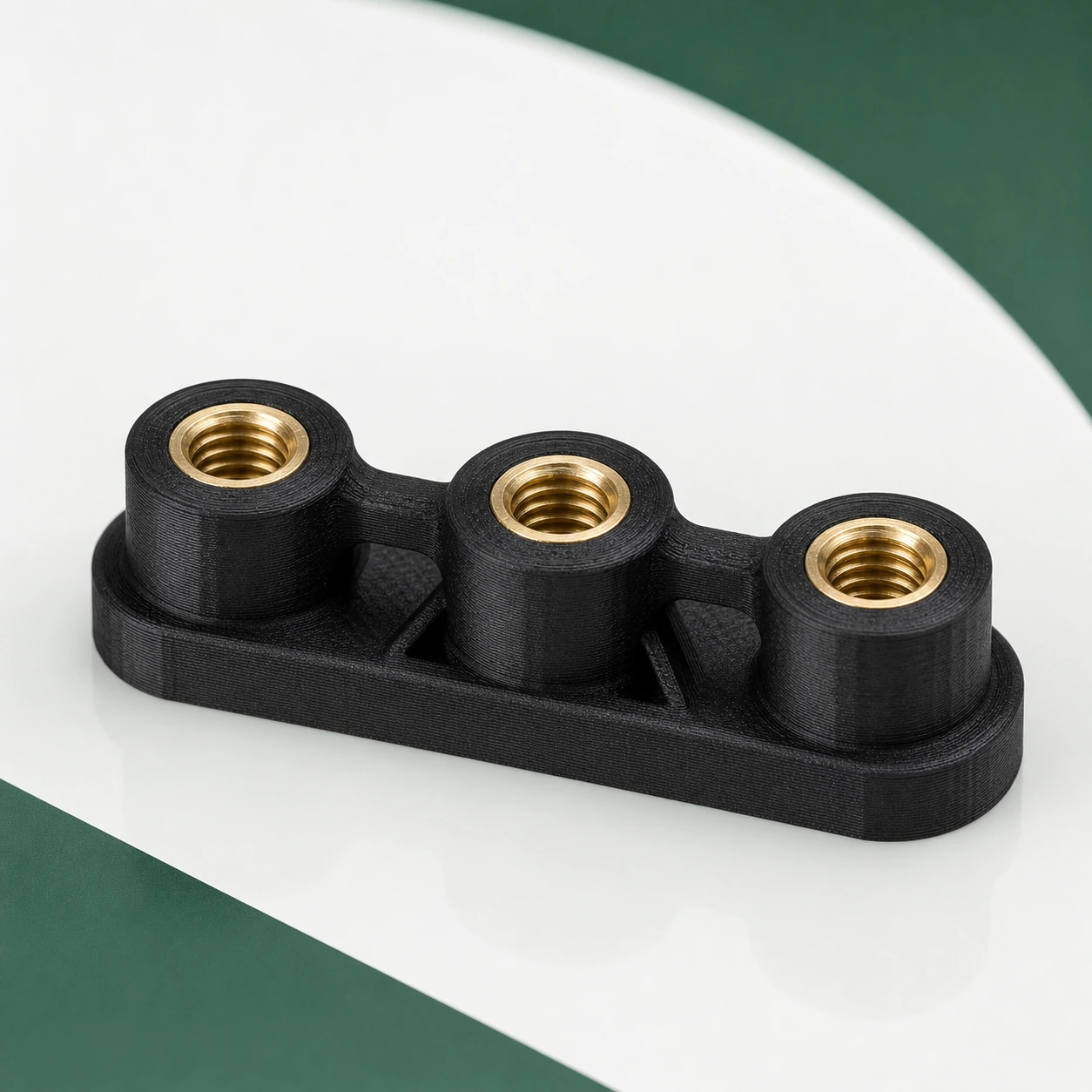 Black PAHT-CF: black PAHT-CF insert boss fixture holding three plain brass threaded inserts, all parts fully visible and unmarked