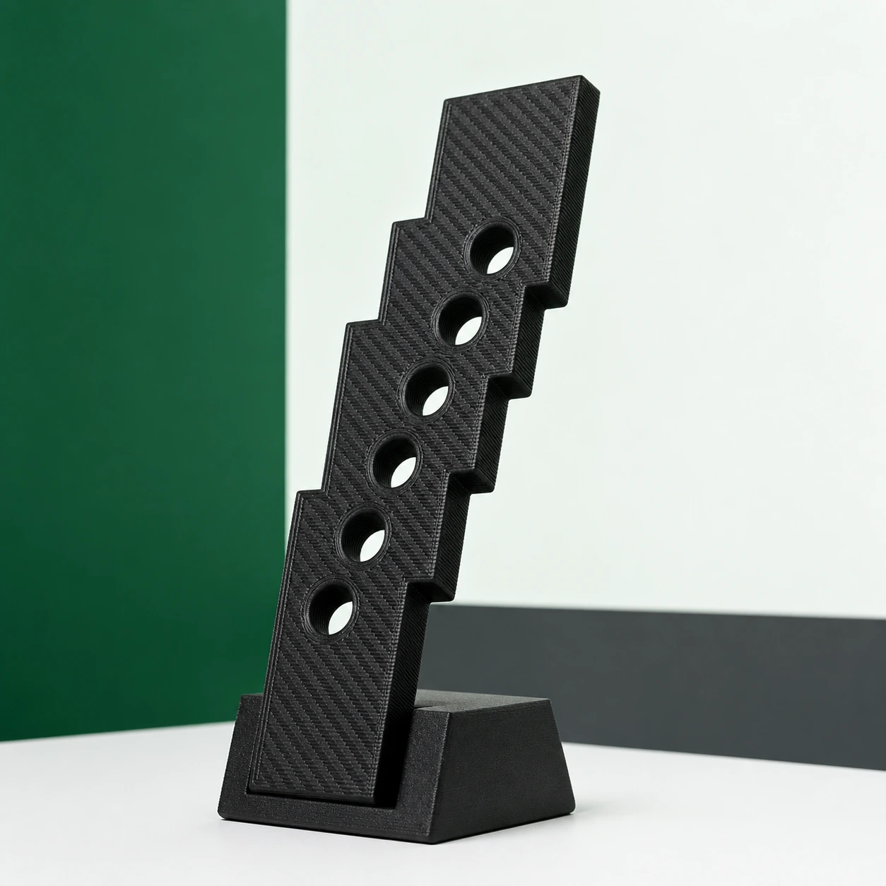 Black PAHT-CF: zigzag stair-step bore coupon with an angled outer edge and six clean unmarked holes arranged diagonally, held at a strong three-quarter angle in a low stand